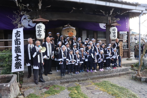 古市義士祭と書かれた幕のよこで整列する衣装を着た子どもたちと横でマイクで話す大人