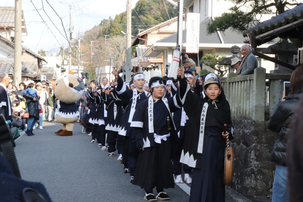 衣装を着た子どもたちが手を振り上げながら道を歩く様子