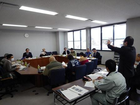 会議室内で起立し発言をする委員と着席して聞いている委員たちの写真