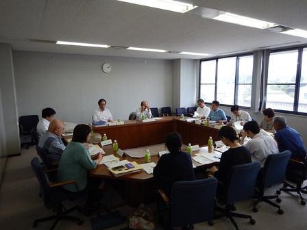 様々な年代の委員が会議室内に集い会議を行っている写真
