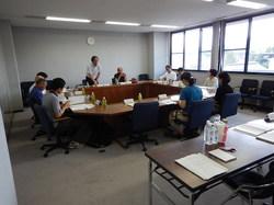 時計が3時を示す会議室内で集まった委員たちが会話している写真