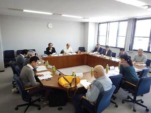スーツや私服姿で会議室に集まり会議を行う委員たちの写真