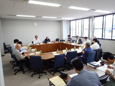 会議室で着席し、資料を手に会議を行う委員たちの写真