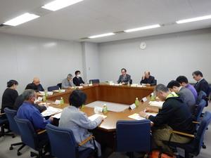 会議室で資料に目を通しながら話し合う委員たちの写真