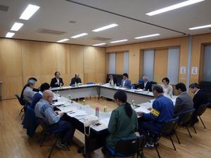 室内で机を四角く並べて会議をする委員たちの写真