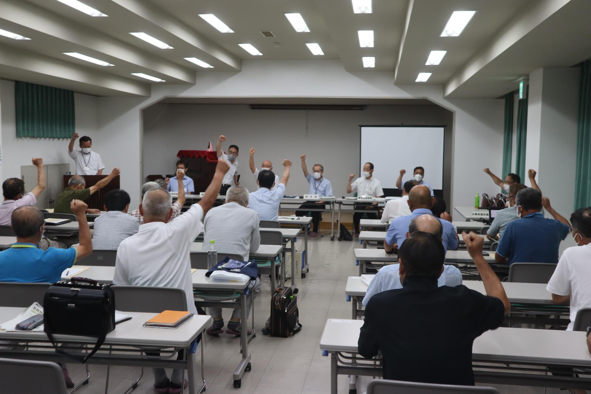 会議の最後に、参加者全員でこぶしを出して「ガンバロー」と言っている