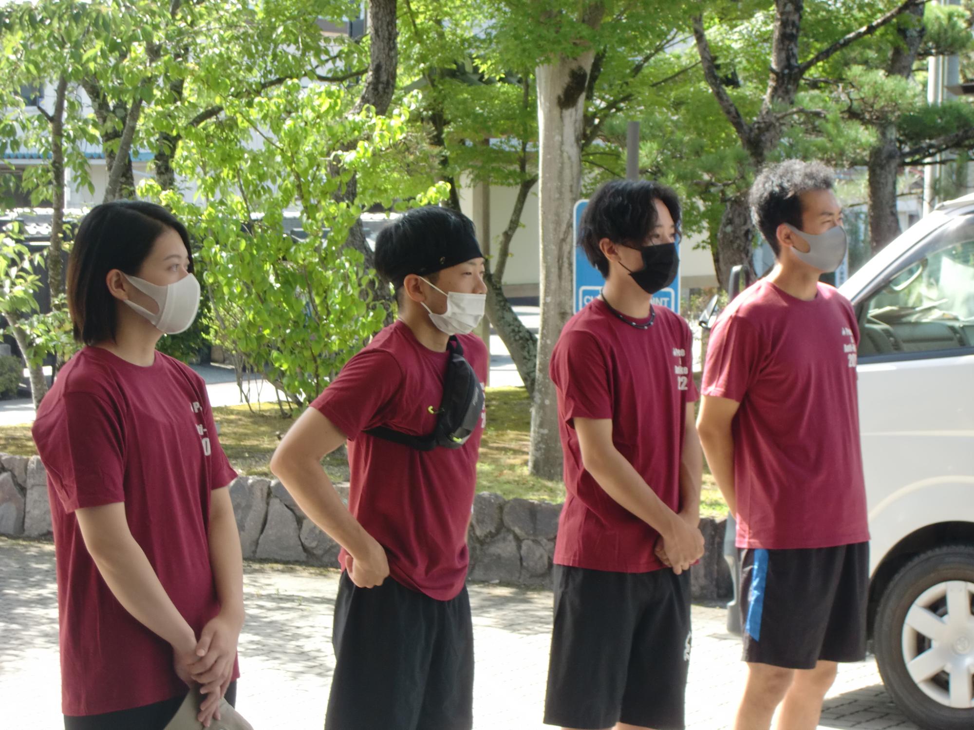 おそろいの赤いシャツを着た4名のランナーが並んで立っている