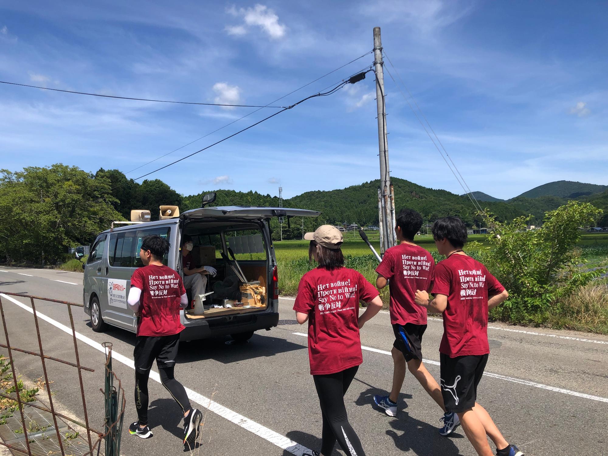 箱バンを先頭に、トーチを持った4名のランナーが走っている。