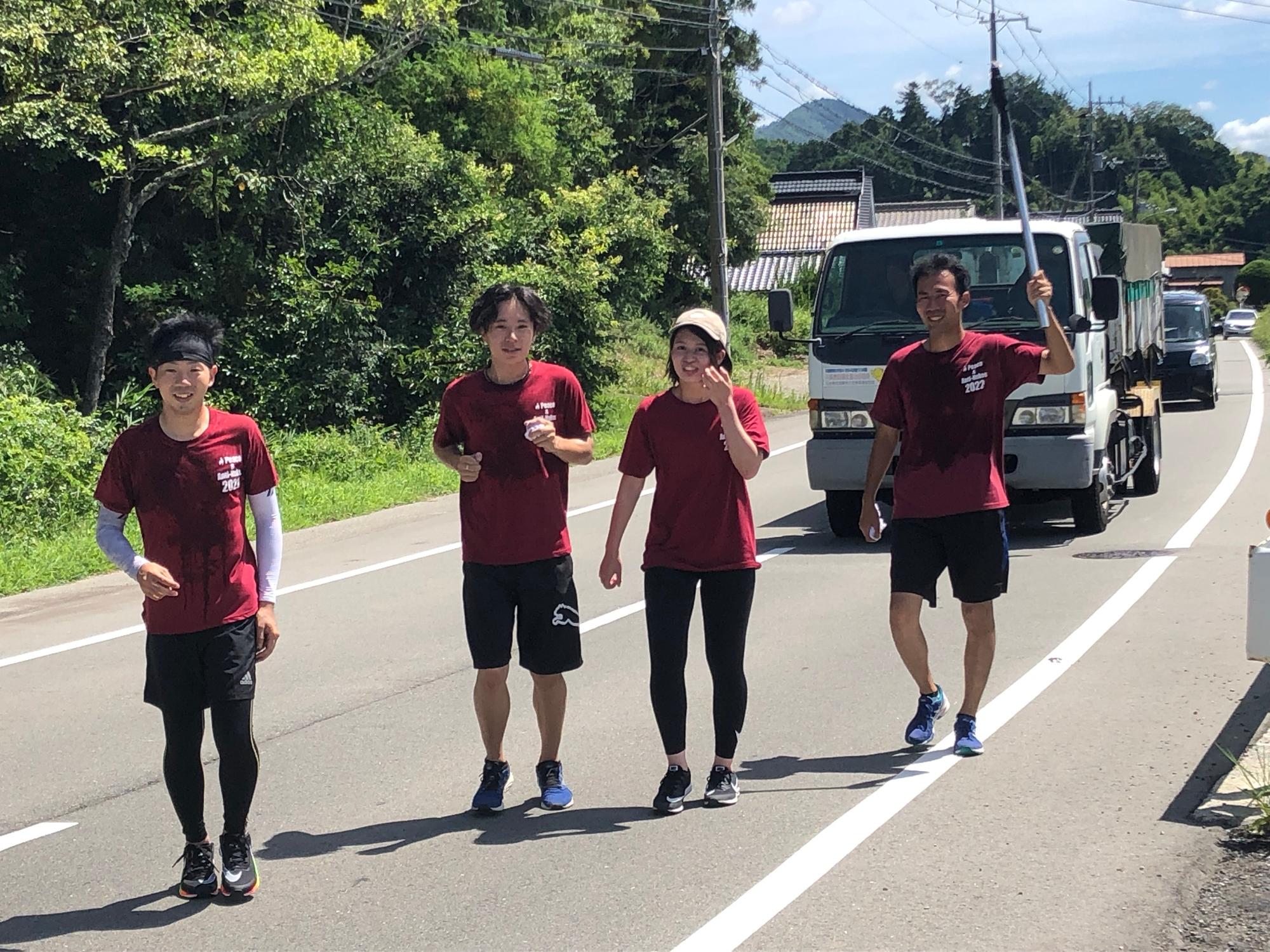 トーチを持った男性と、3名のランナーが走っている