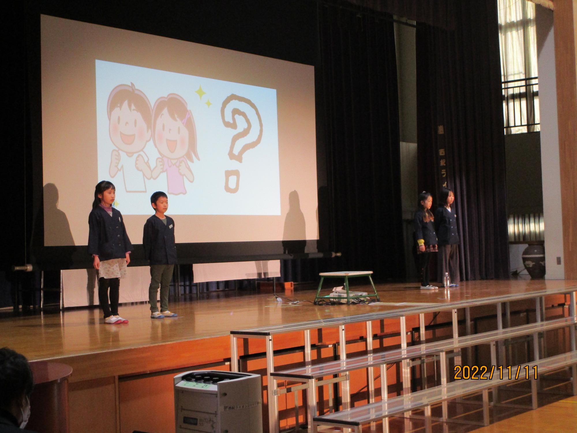 スライドを使って、子ども達が舞台の上で発表している