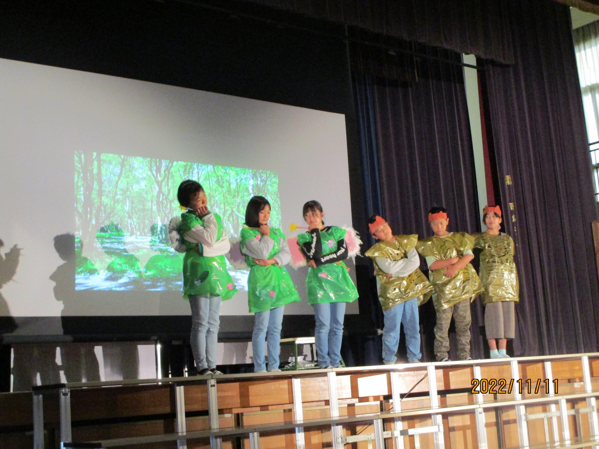 おそろいの衣装を着た子ども達が、スライドを使って発表している