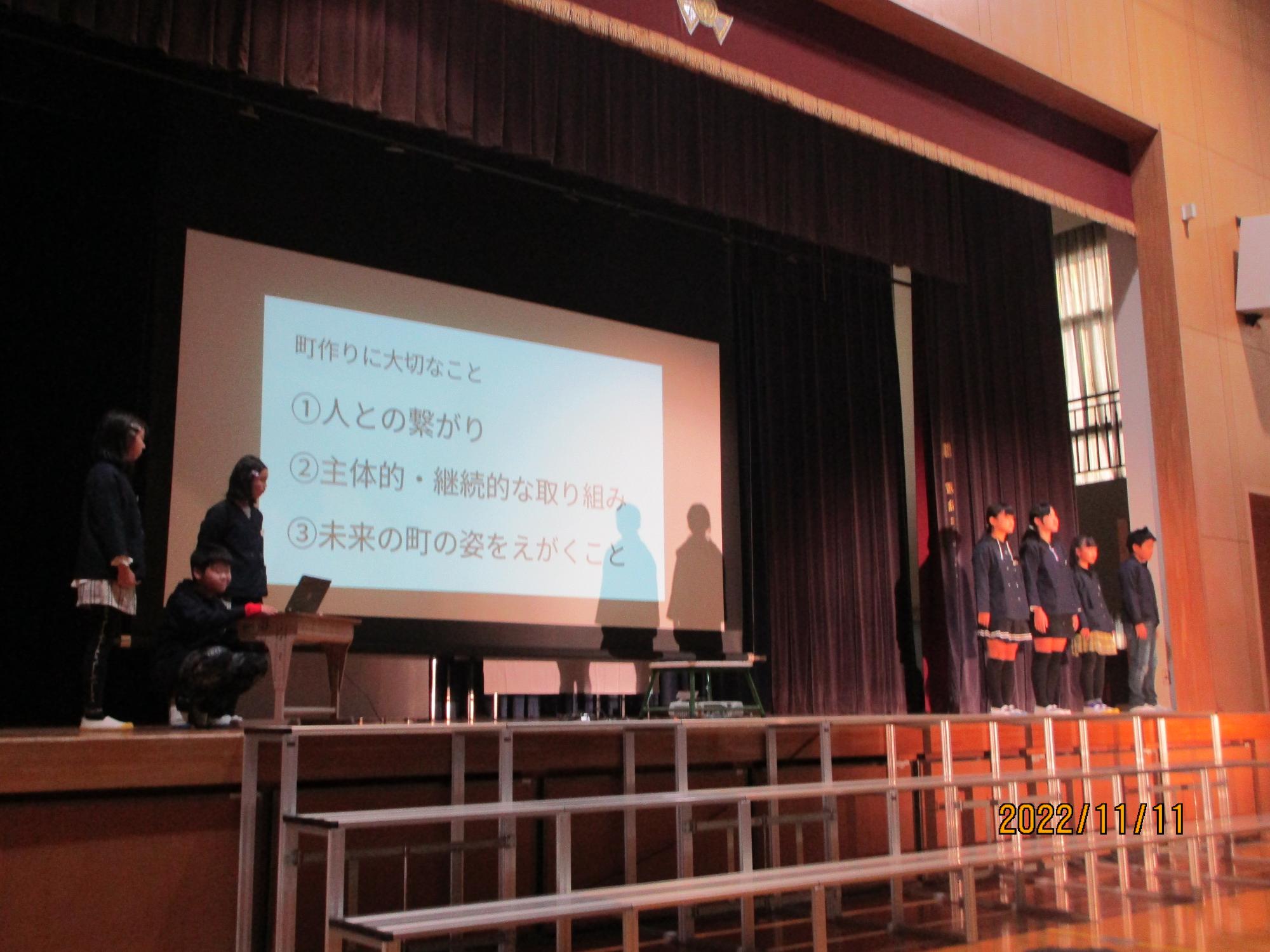 スライドを使って、子ども達が舞台の上で発表している