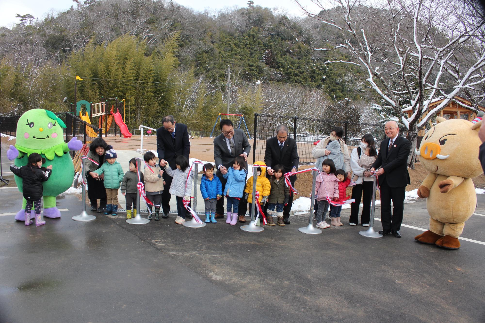 こどもたち、市長、教育長、関係者の皆さん、まるいの、まめりんがテープカットをしている