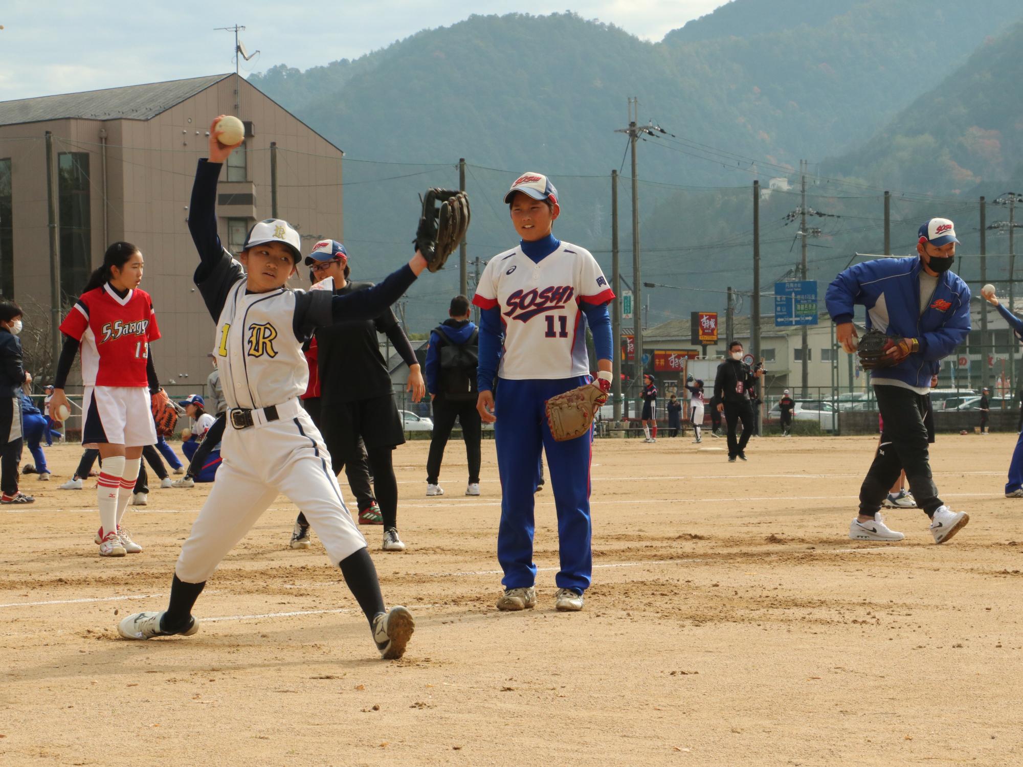 ソフトボールの交流試合でピッチングの指導をしている