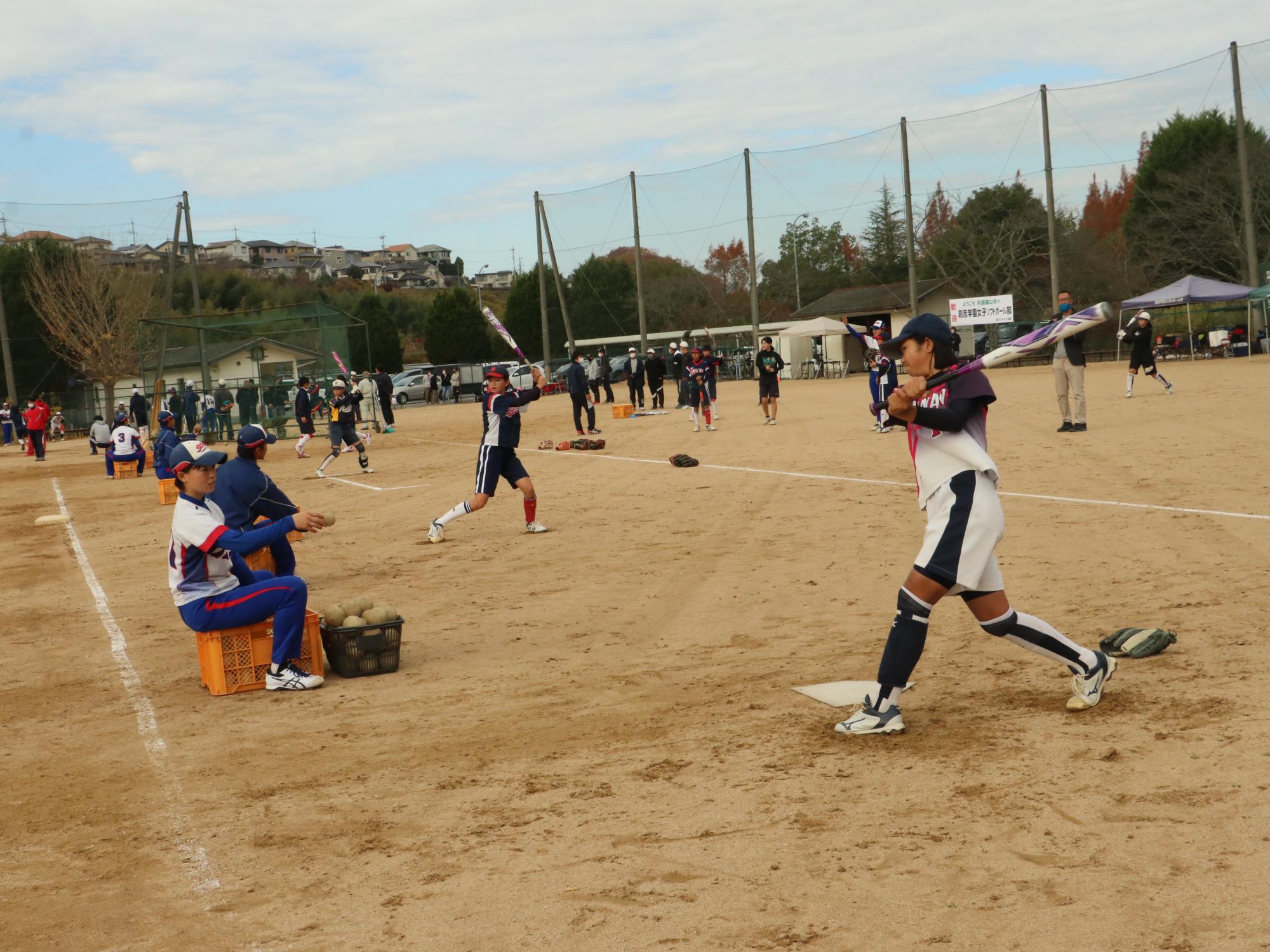 ソフトボールの交流試合でバッティングの練習をしている