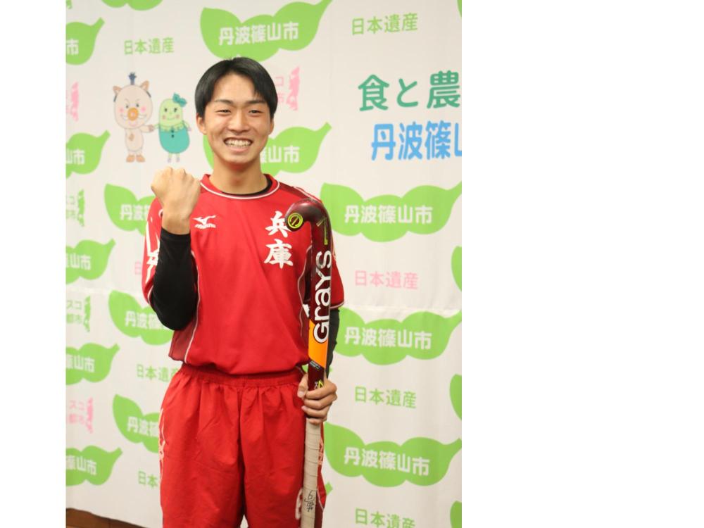 ホッケーのユニフォームを着た代表選手が、ガッツポーズをして記念撮影