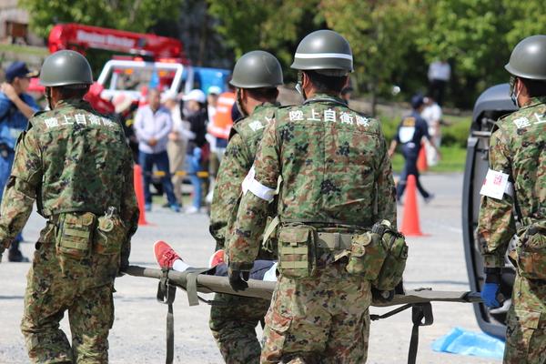 4名の陸上自衛隊の人たちが担架で人を運ぶ訓練をしている写真