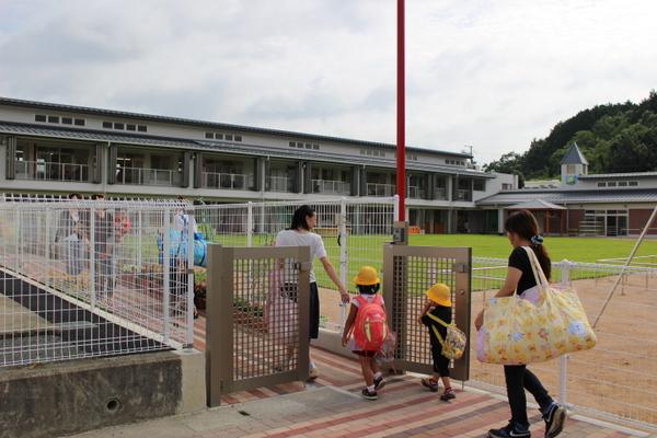 保護者に手を引かれ、園に登園している子供の写真