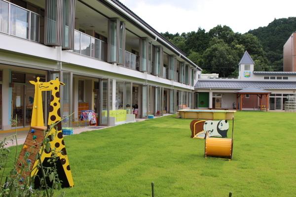 園内に芝生が敷かれ、キリンやパンダの形をした遊具が置いてある写真