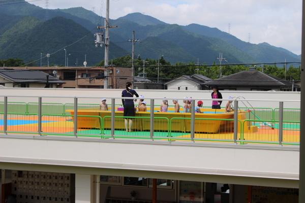 園の屋上に仮設プールが設けてあり、プールの中で遊んでいる子供たちの写真