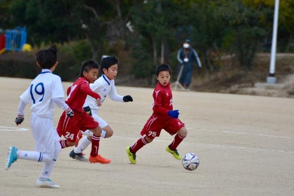 子供達がサッカーの試合で一生懸命プレーしている写真