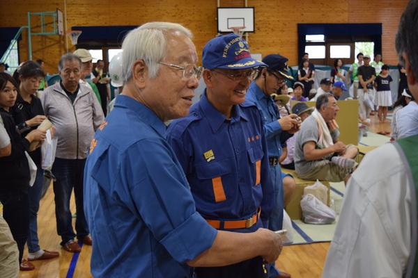 体育館の中で作業着を着た市長と男性職員が市民の方と話をしている写真