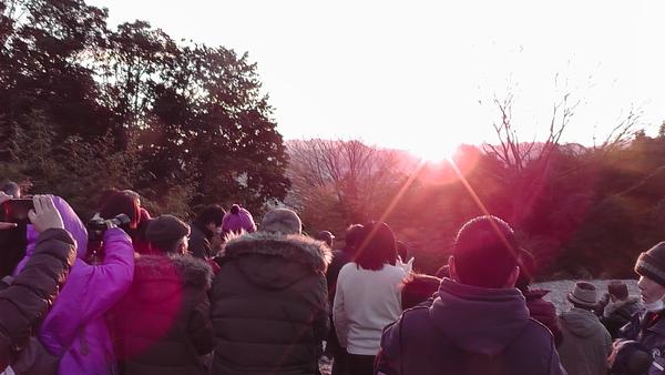 朝日が昇る様子を眺めたりカメラで撮影しようとしている人々の写真