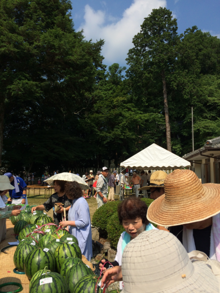 沢山のスイカが並べられており、そのスイカを買いに来られた方々の写真