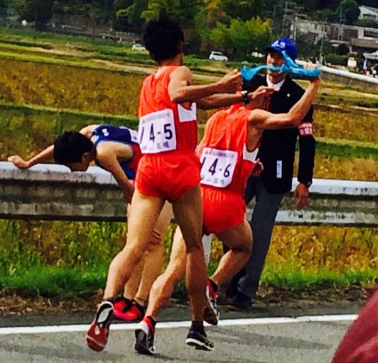 篠山鳳鳴高等学校の生徒が次のランナーにタスキを渡す様子を後ろから写した写真