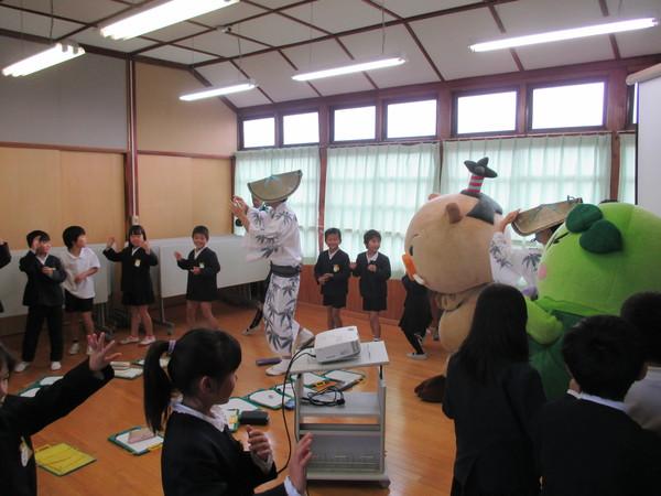 子供達がゆるきゃら2体と編み笠を被った踊り子2名と一緒に両手を挙げて踊っている写真