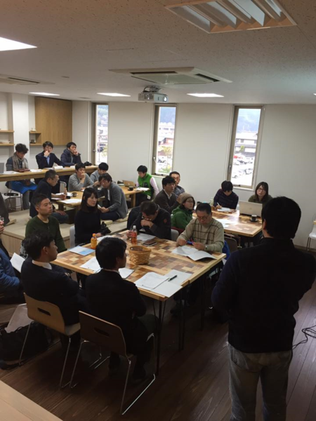 男性が代表で前に立ち、受講生が話を聞いている写真