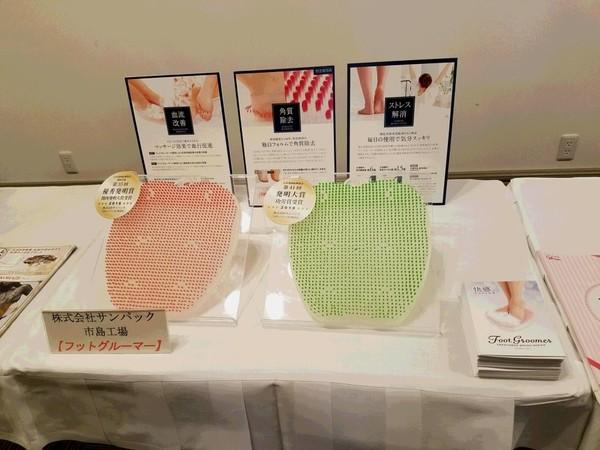 お風呂で使うフットブラシがパンフレットやパネルと一緒にテーブルに展示されている写真