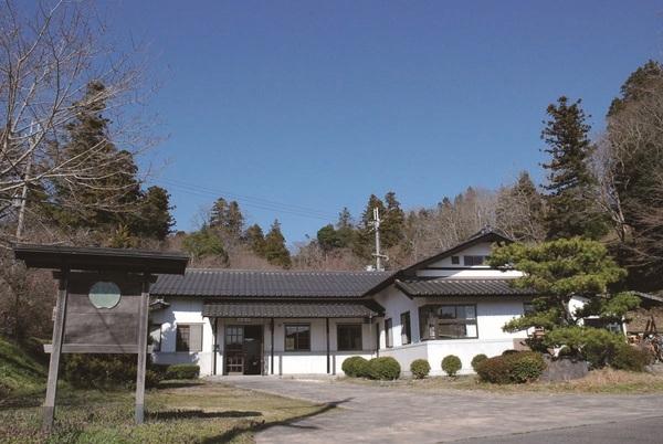 青空の木々中にたつ白が基調の王地山陶器所の外観写真