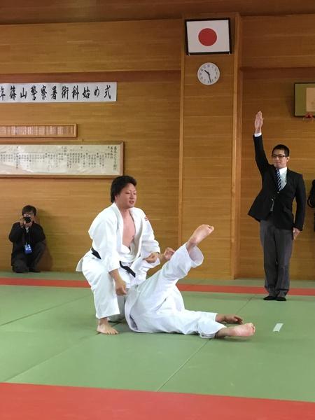 柔道の試合で黒帯の選手が技を決め審判が直立不動で右手を挙げている写真