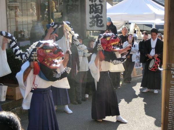 獅子頭を頭にかぶって舞う2頭が披露されている様子を見物客の方が写真を撮ったりしている写真