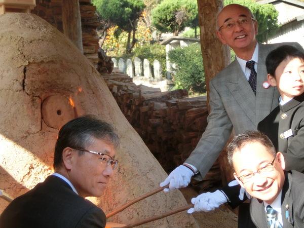 市長、制服を着た男の子、男性2人で火を入れているアップ写真