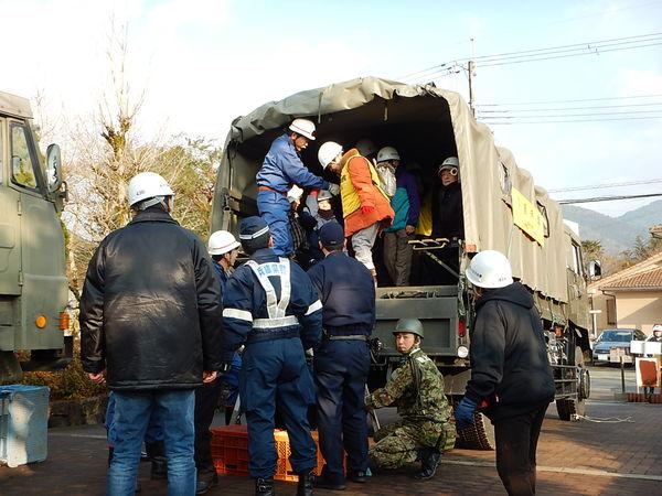 自衛隊の車の荷台に人が乗っていて、車から人を降ろす練習をしている写真