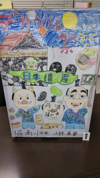 イメージキャラクターと市長がお祭りを楽しんでいる似顔絵、優秀賞の小林 美葵さんの作品の写真