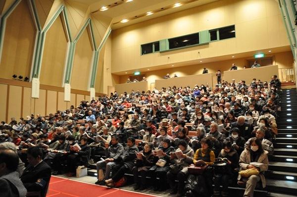 ホールいっぱいに集まった「守ろう!特産「山の芋」広げよう!グリーンカーテン」の催しを参加者が聞いている写真