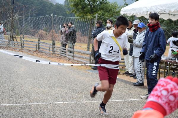 体操服を着た男子生徒がゴールテープを切った写真