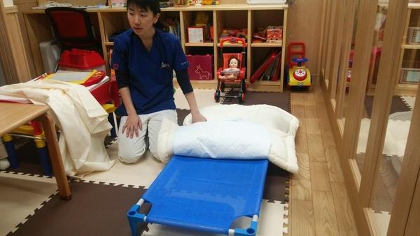 部屋に置かれた簡易式の青いベッドの写真