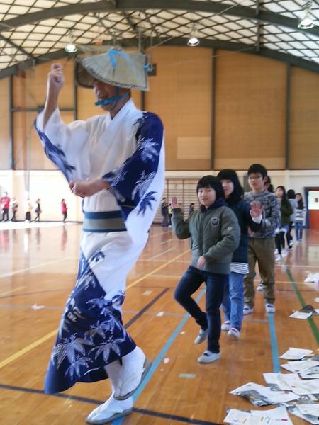 浴衣を着た男性が先頭で踊り、その後ろから子供達が真似をして踊っている写真