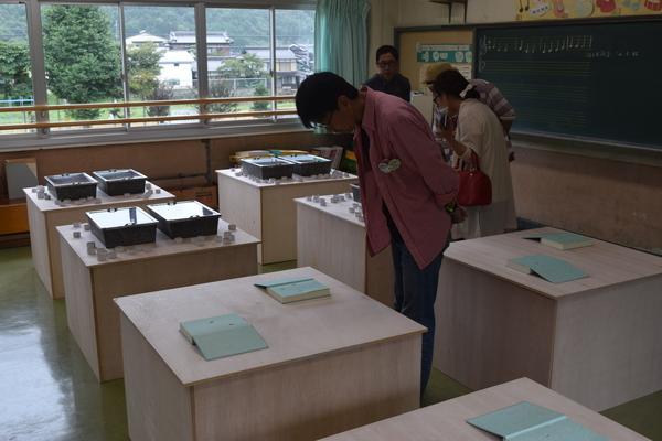 テーブルの上に本で作られた作品が置かれていて、それを男性がのぞき込んで見ている写真