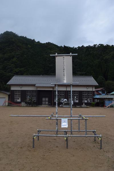 奥には家が一軒あり、その手前に鉄骨で作られたオブジェが飾られている写真