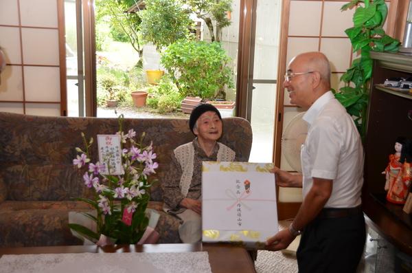 男の方がソファに座っているご高齢の女性に商品を渡している写真