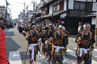 武者姿の少年達の行列が笑顔で練り歩いている写真