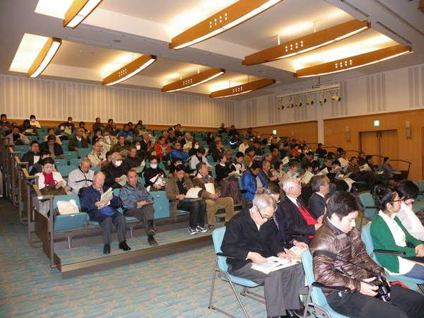 資料や、メモを取りながら聞く聴衆者の写真