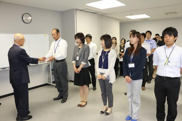 男性2名、女性3名が前に立ち、男性が市長から辞令交付を受け取る写真