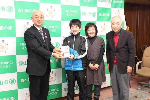 市長から目録を渡されている酒井君が母親と祖父も一緒に記念撮影している写真