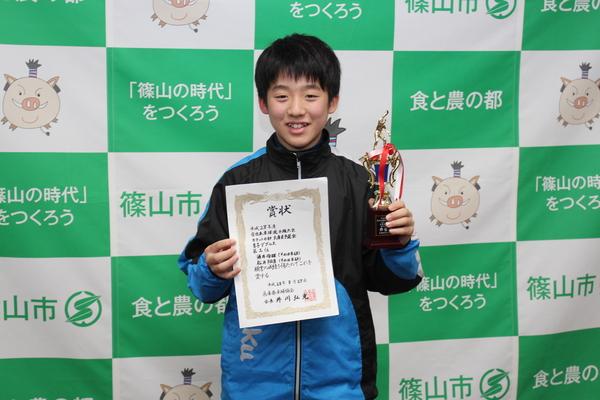 賞状とトロフィーを手にした中学生の酒井君が笑顔で記念撮影している写真